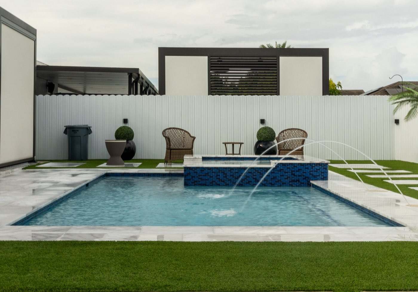 Custom rectangular pool with raised blue-tile spa and marble deck built by Florida Blue Waters in Miami, FL